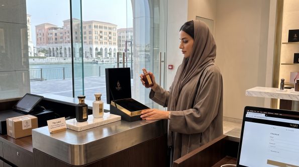 WAJD Fragrances shipping and returns: woman placing a WAJD bottle in its gift box at a Doha boutique checkout counter