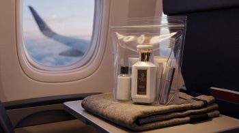 Flying with perfume: WAJD SABAH bottle in a clear liquids bag on an airplane tray table by the window